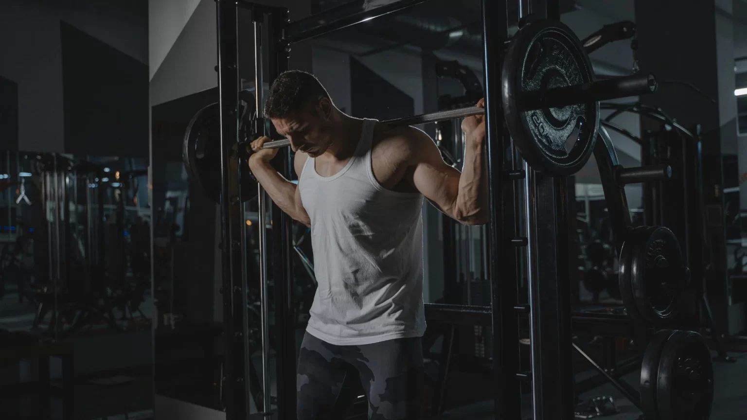 Man performing barbell squat workout in a modern gym in Hyderabad for strength training, muscle building, and fitness improvement.